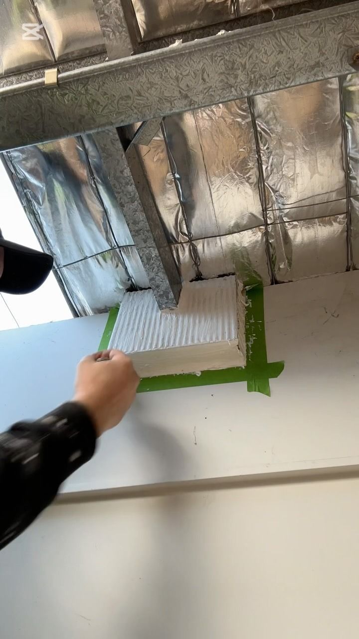 Person Applying White Insulation With Green Tape on a White Wall — Hunter Fire & Safety in Coffs Harbour, NSW