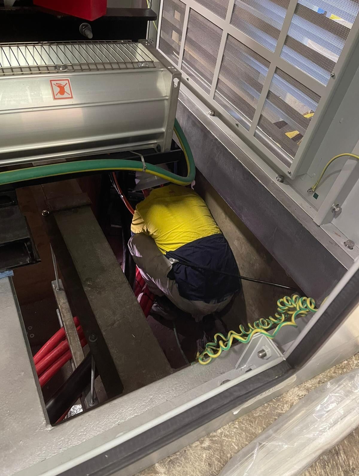 Person in Yellow Vest Working Inside an Electrical Cabinet — Hunter Fire & Safety in Coffs Harbour, NSW