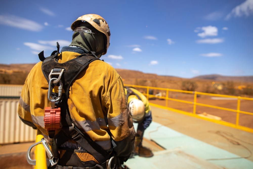 Worker in Safety Gear, Harness Attached, Looking at Another Worker on a Platform — Hunter Fire & Safety in Coffs Harbour, NSW