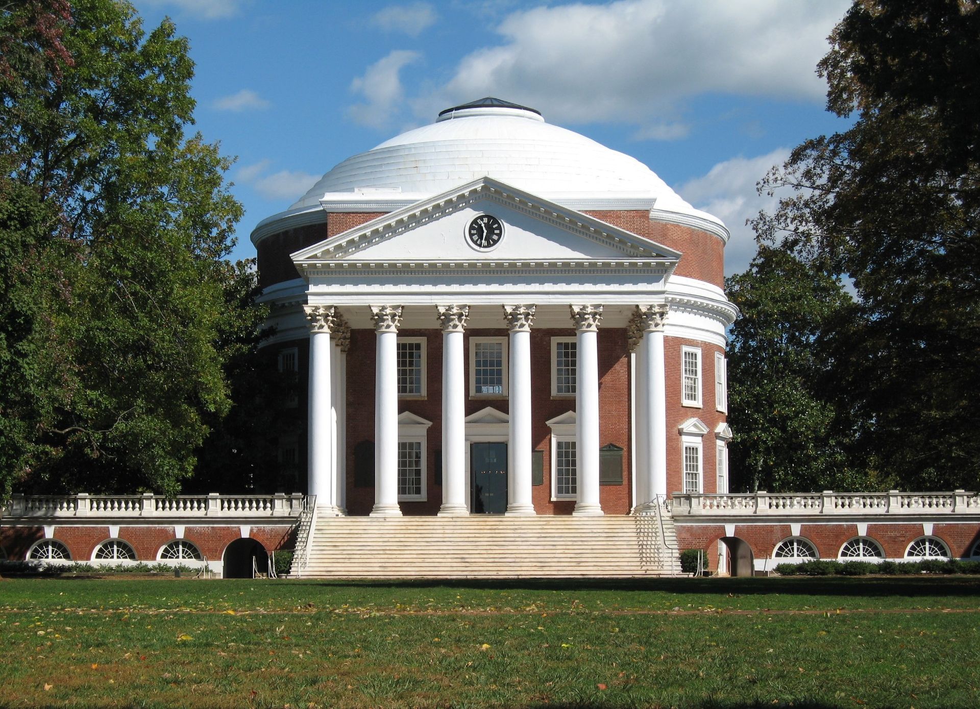 Rotunda building, University of Virginia, white columns, red brick, dome, green lawn, trees.