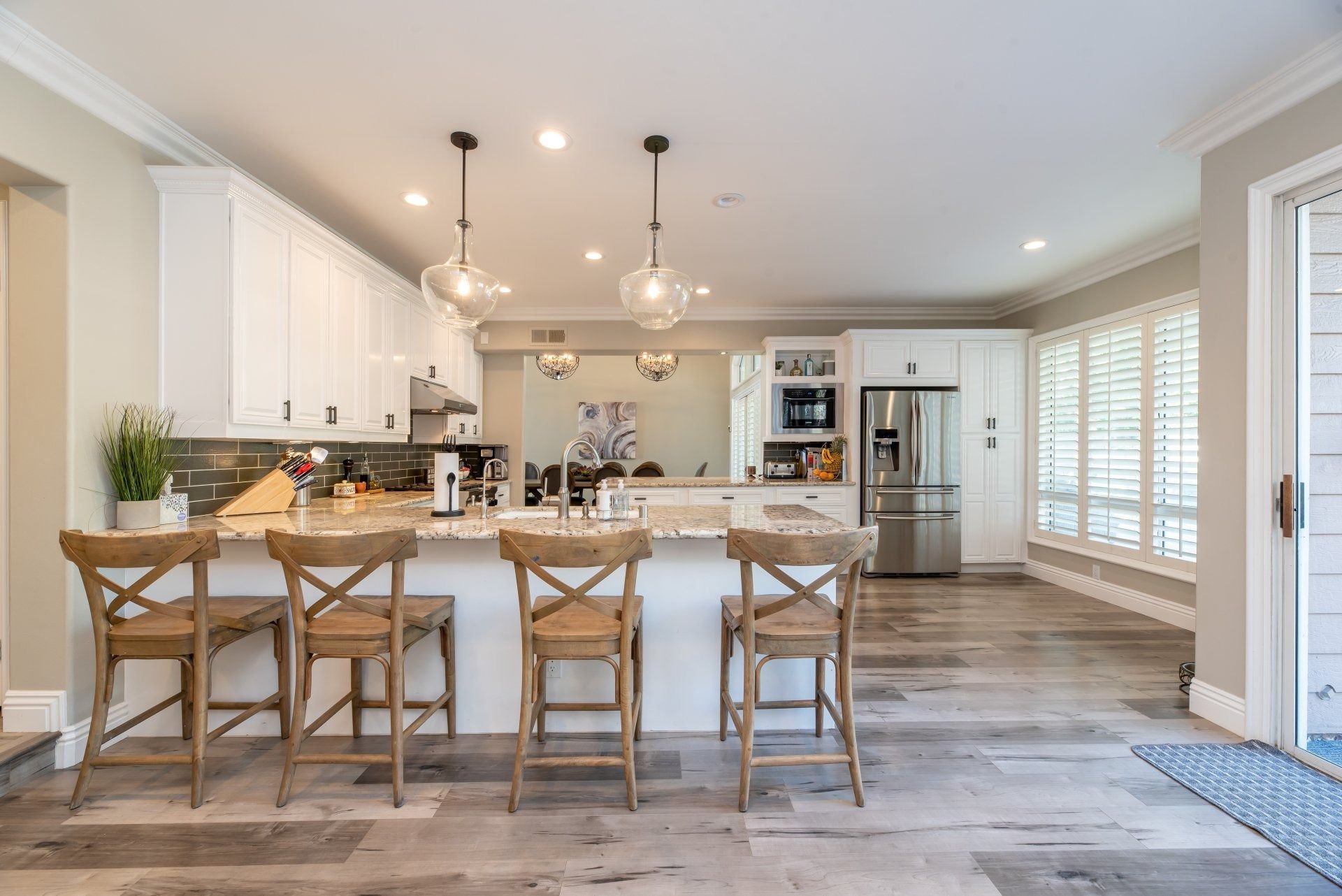 Kitchen with white cabinets, granite island, wooden stools, and hardwood floors.