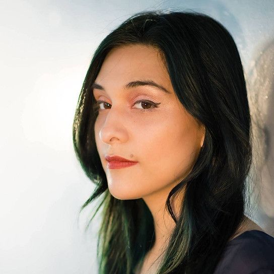 Portrait of a woman with long dark hair against a light background