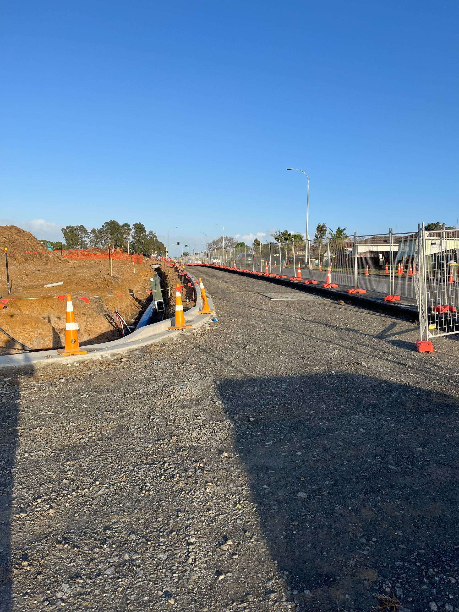 A train track is being built next to a gravel road.