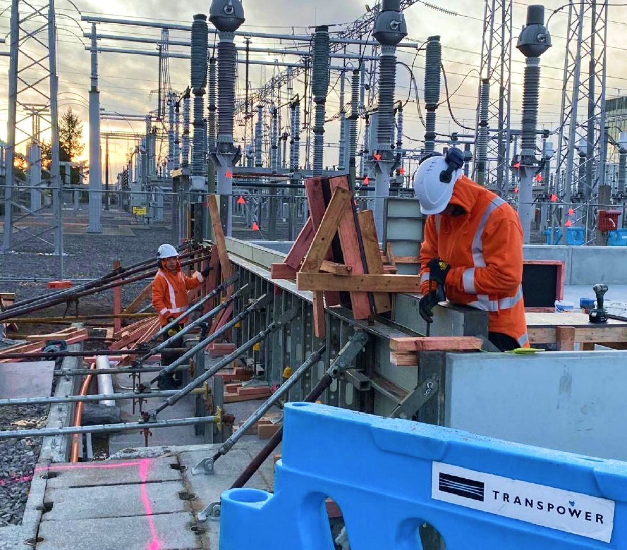A man is working on a construction site next to a blue barrier.