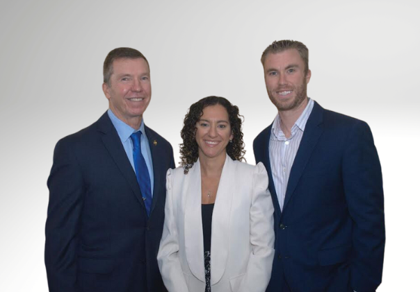 Three people posing together against a white background, wearing business attire and smiling.