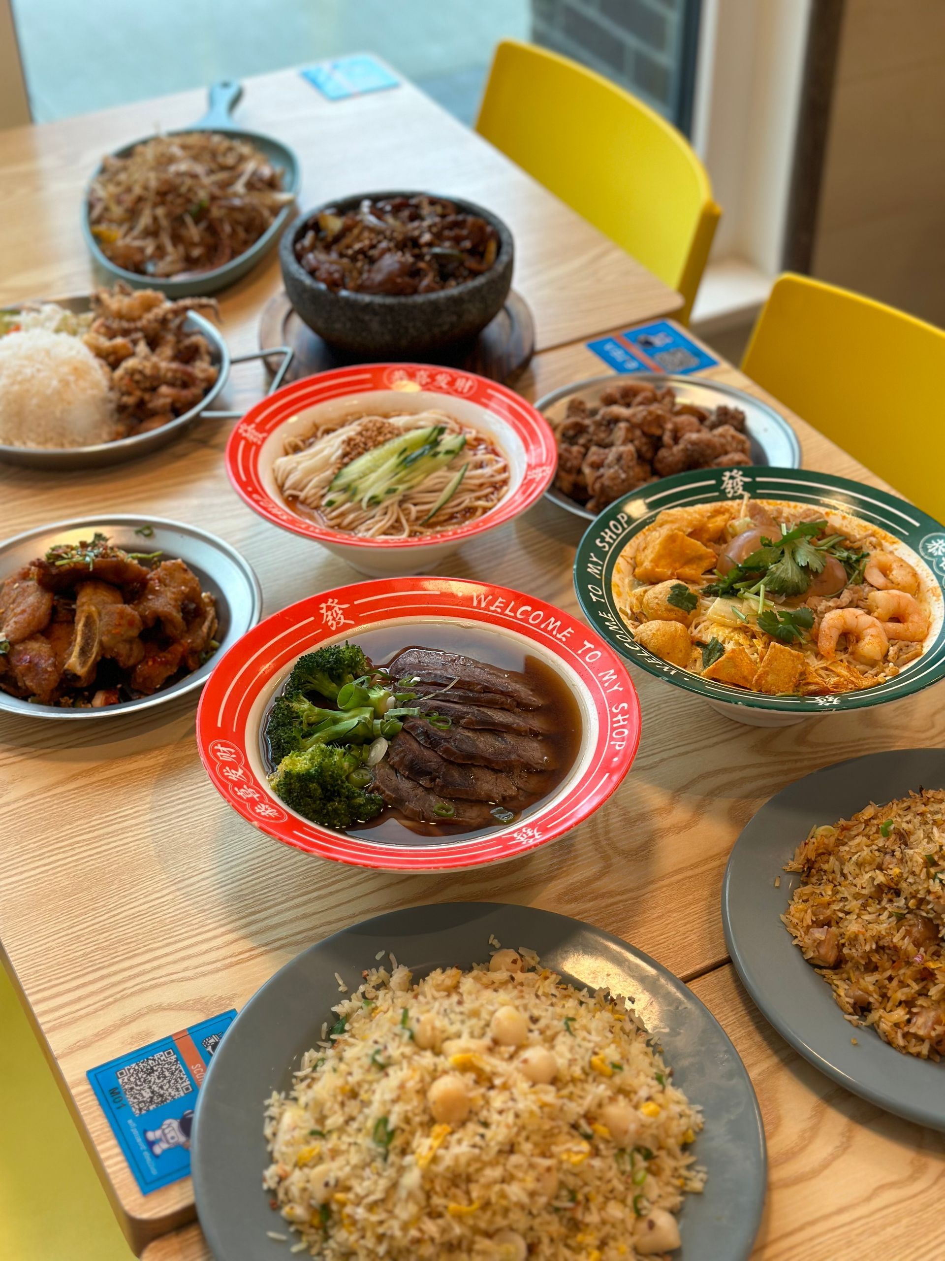 Assorted Asian dishes on a table with rice, noodles, curry, and fried items in takeout containers