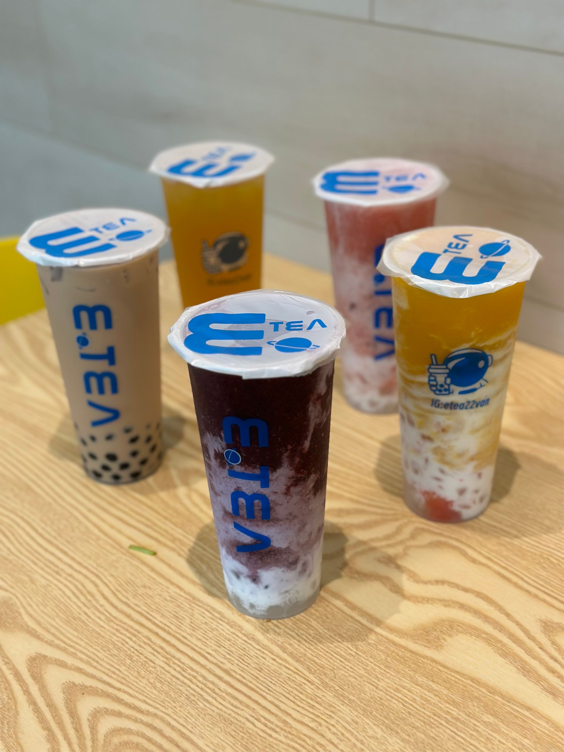 Five colorful dessert cups with blue lids arranged on a wooden table