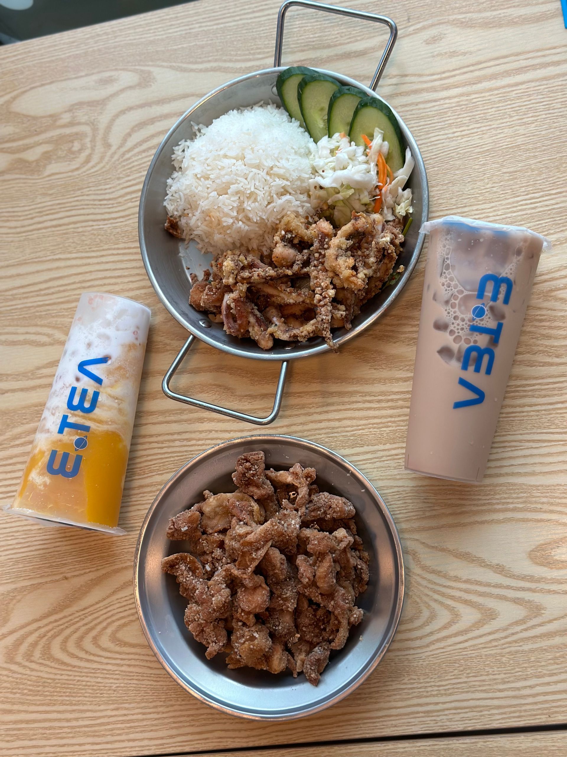 Two bowls of rice and meat on a wooden table with two cans of Eeva drink.
