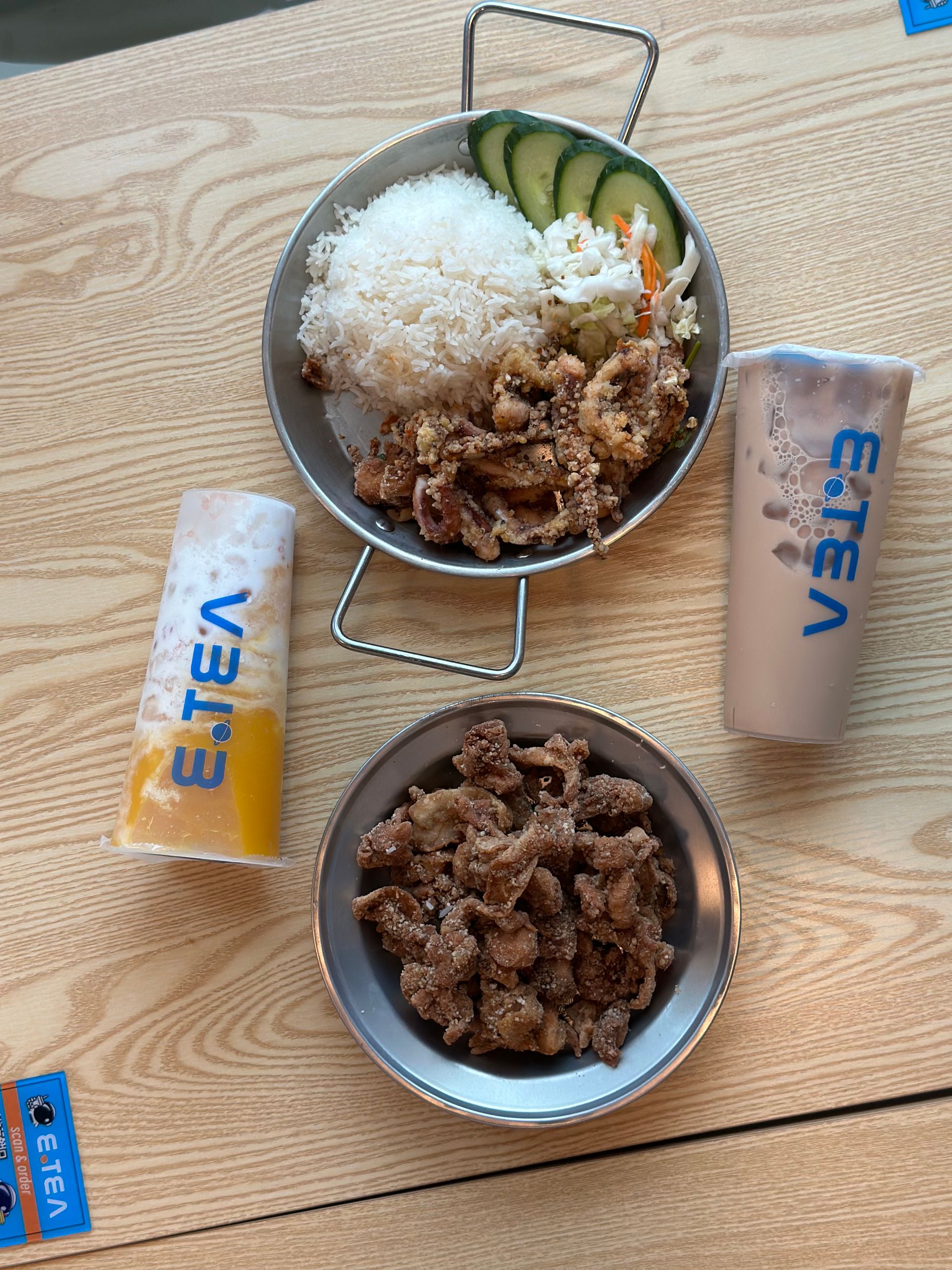 Two bowls of beef rice with cucumbers on a wooden table, beside two ETEN drink bottles.
