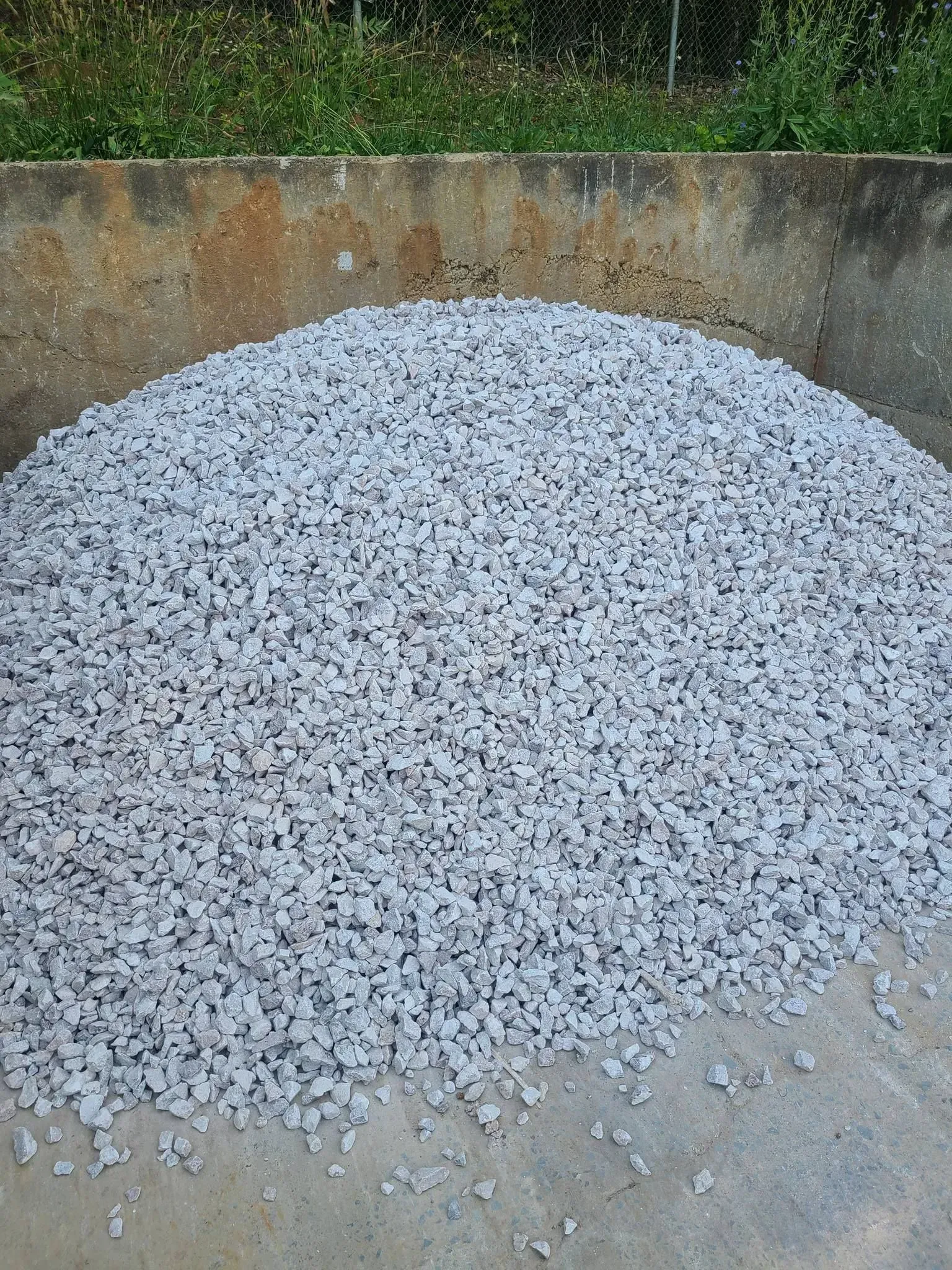 Large pile of white gravel or crushed stone in a concrete area outdoors