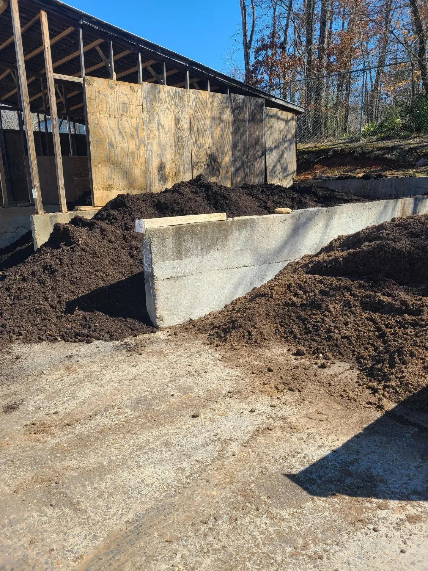 Concrete retaining wall beside a building under construction, with dirt and gravel piled around it