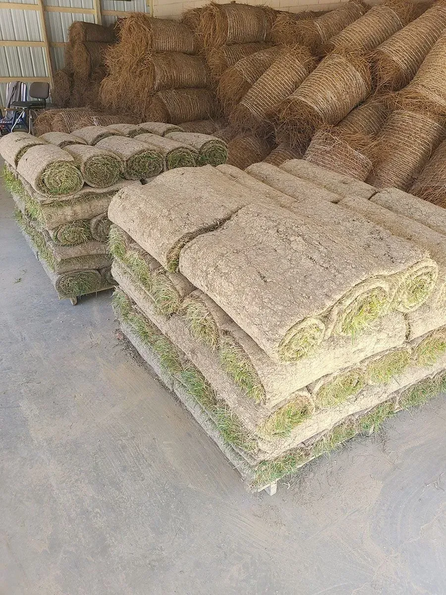 Stacked folded mats or bags of straw-like material in a storage area on a concrete floor