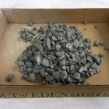 Pile of gray rocks in a cardboard box lined with tan paper.