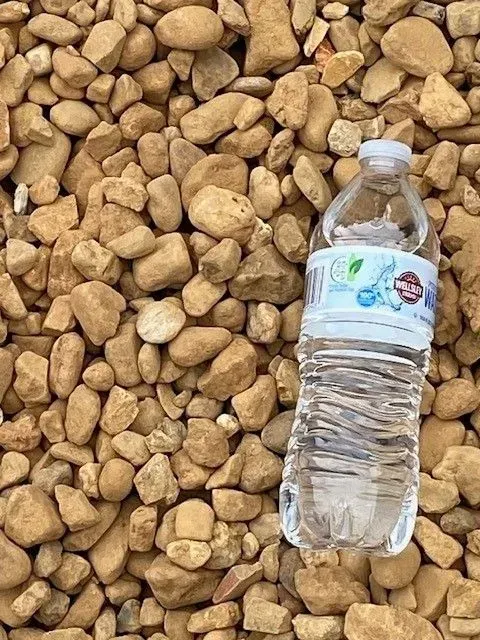 Clear plastic water bottle lying on tan gravel stones