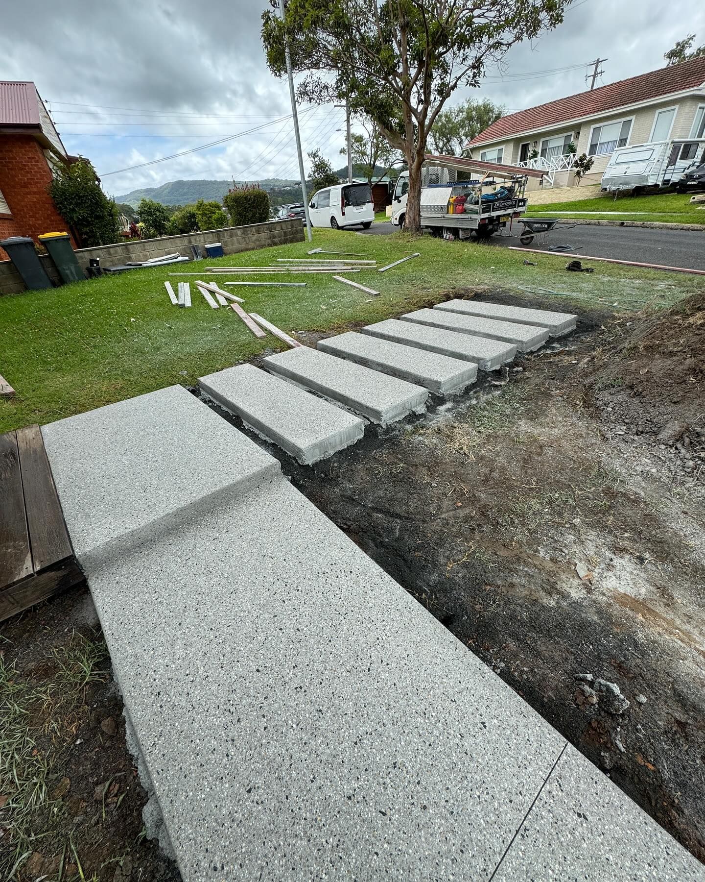 A Light-gray Stone Walkway Leads From a Wooden Deck — JDB Concreting in Horsley, NSW