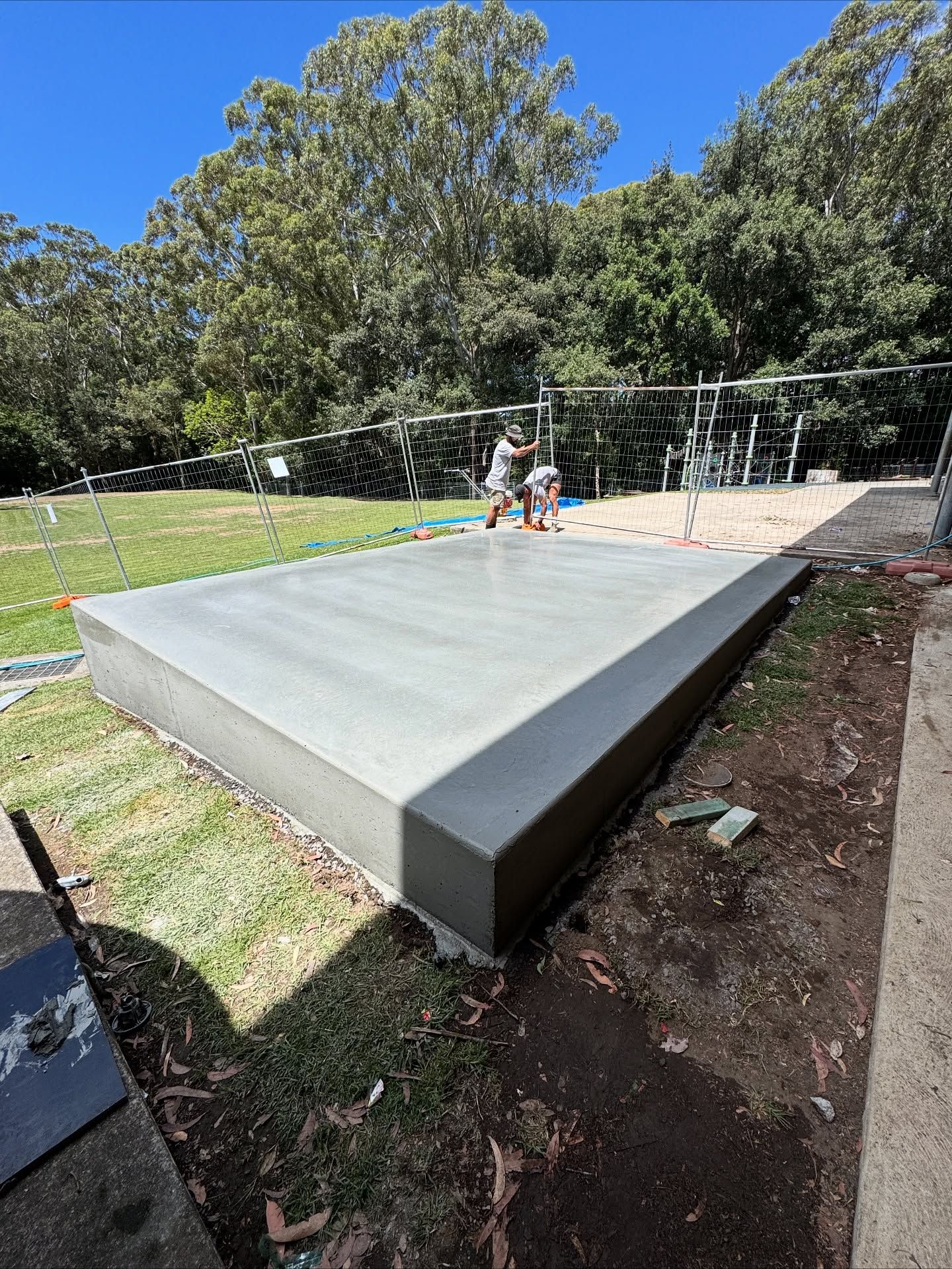 A Freshly Poured Concrete Slab Sits in a Grassy Yard Near a Fence — JDB Concreting in Horsley, NSW