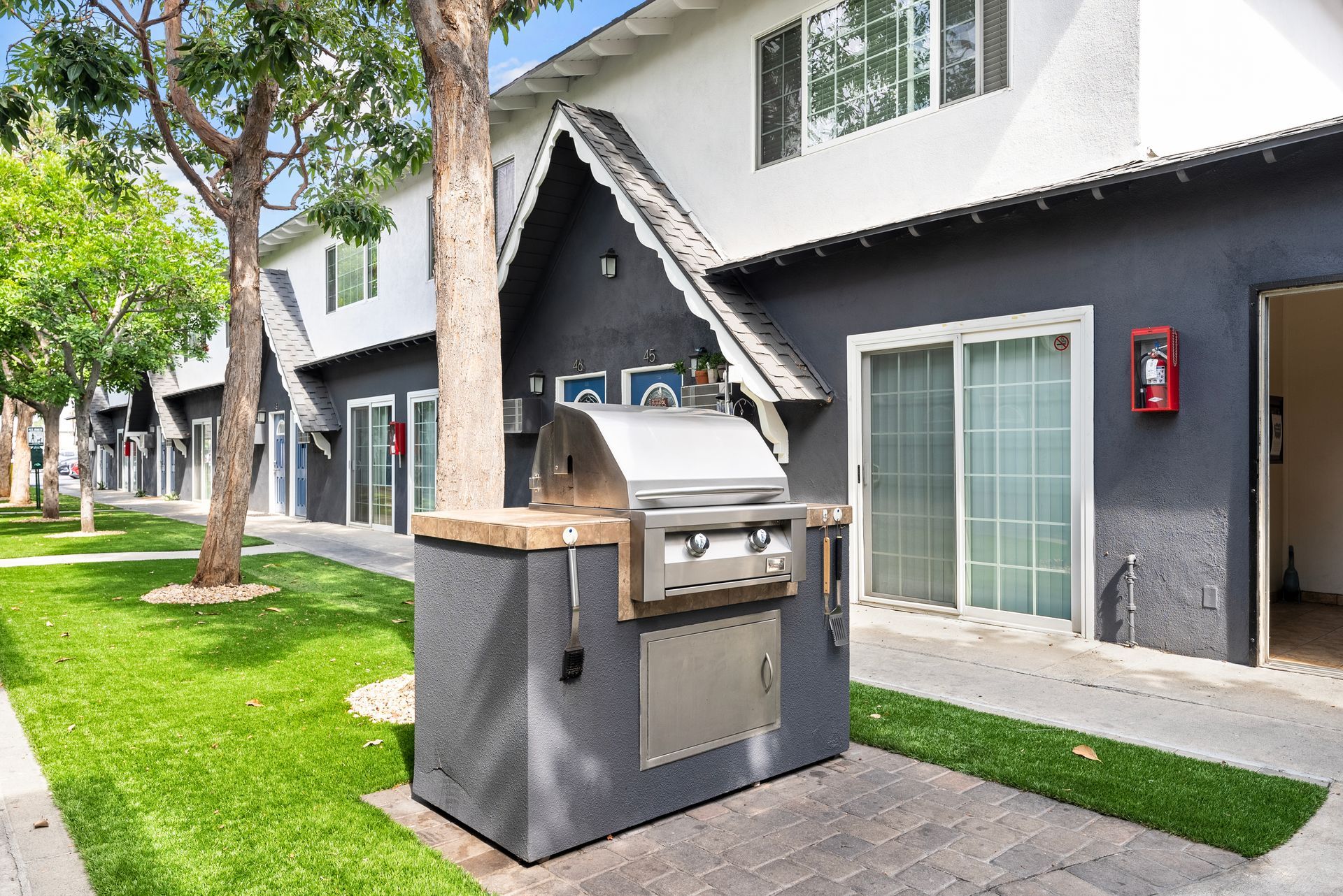 Gallery of exterior and interior photos of Northwind. Including walkways, gray archways, blue front doors, bbq grills, bedrooms with furniture, gated entrances, and main office.