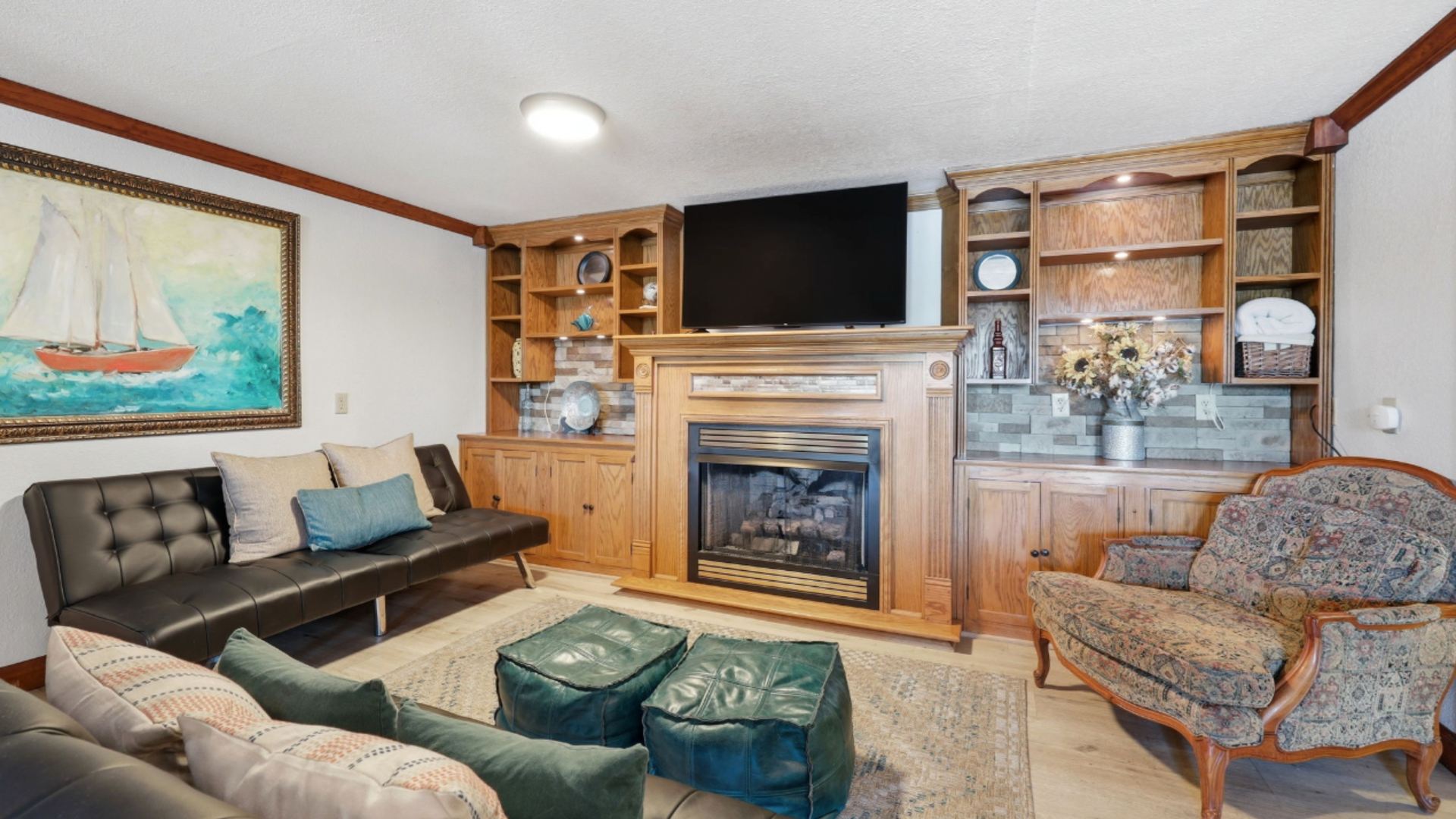 Cozy living room with fireplace, wall-mounted TV, sofa, armchair, and built-in shelves