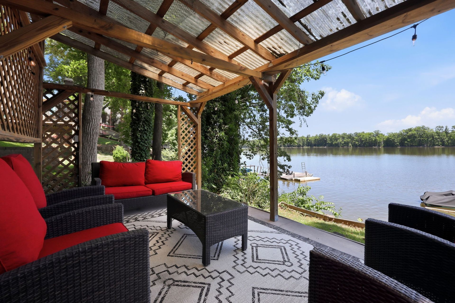 Covered patio with red and black wicker seating overlooking a river and distant trees
