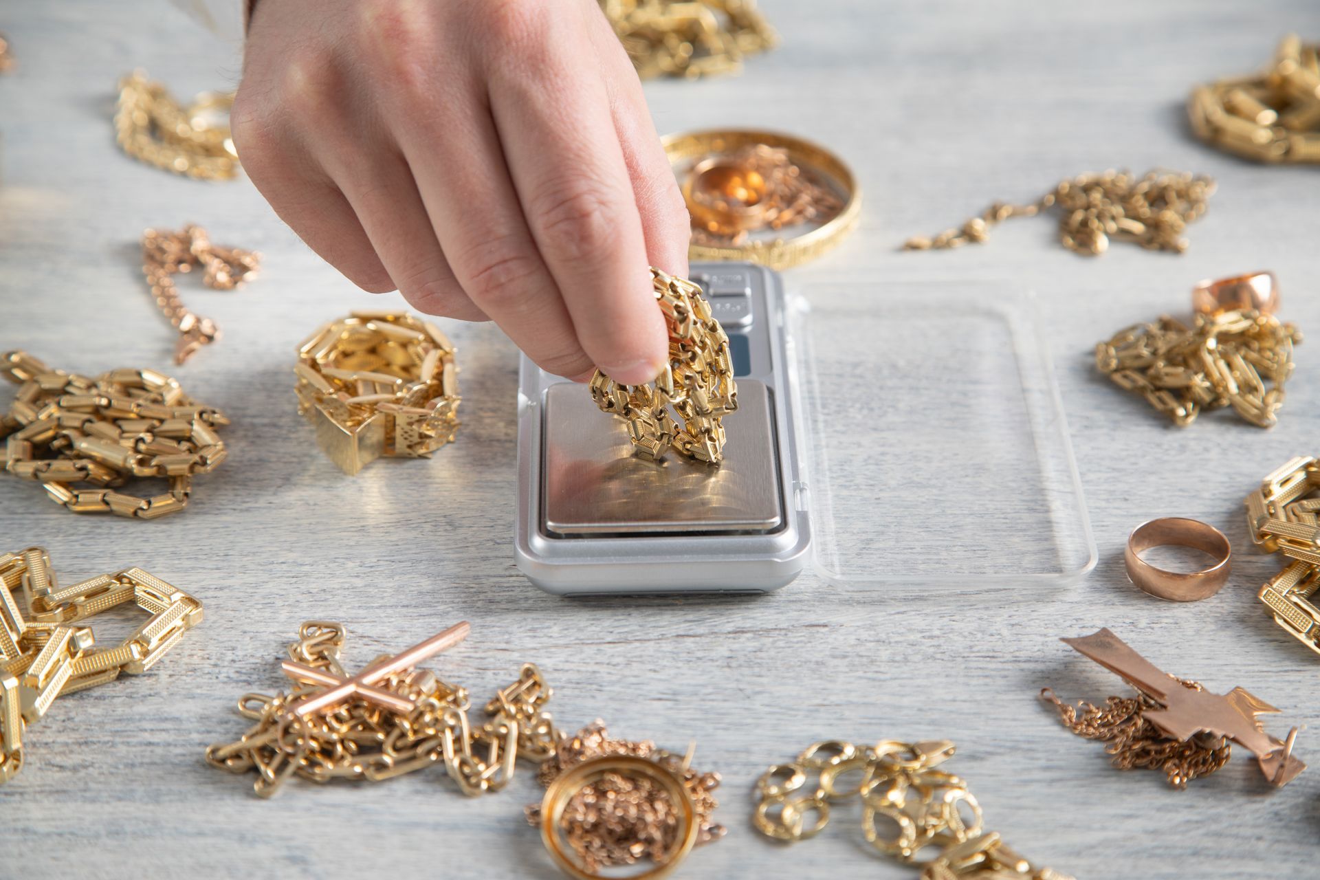 A person weighing gold jewelry on a digital scale, focusing on the precise measurement displayed. A person weighing gold jewelry on a digital scale, focusing on the precise measurement displayed.