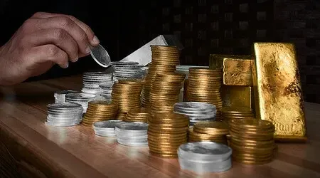 A person is putting a coin into a pile of gold coins.