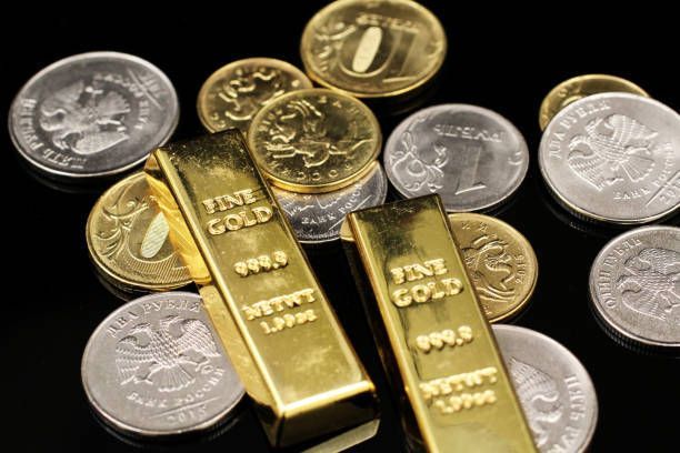 Gold bars and coins on a black surface; the bars read 