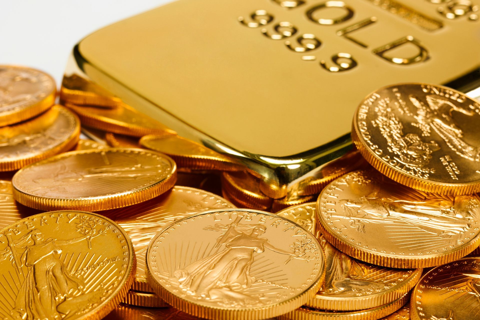 A pile of gold coins next to a gold bar