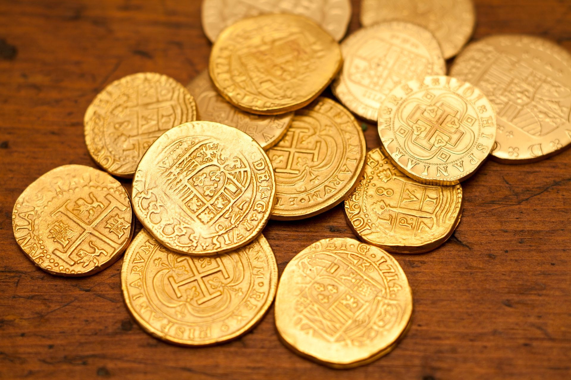 A pile of gold coins on a wooden table