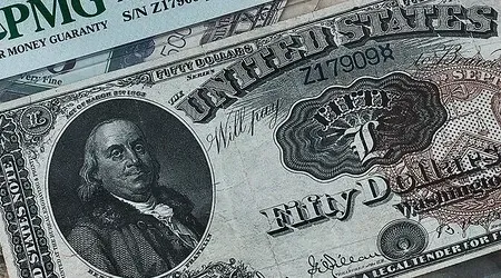 Close-up of a United States fifty-dollar bill, featuring Benjamin Franklin, with a grading certificate partly visible.