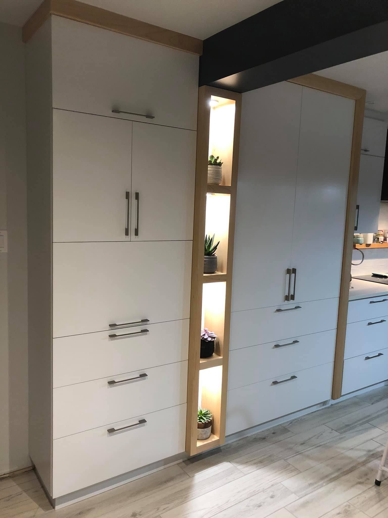 Mur de cuisine moderne avec placards blancs du sol au plafond, moulures en bois et étagère verticale intégrée avec plantes décoratives.