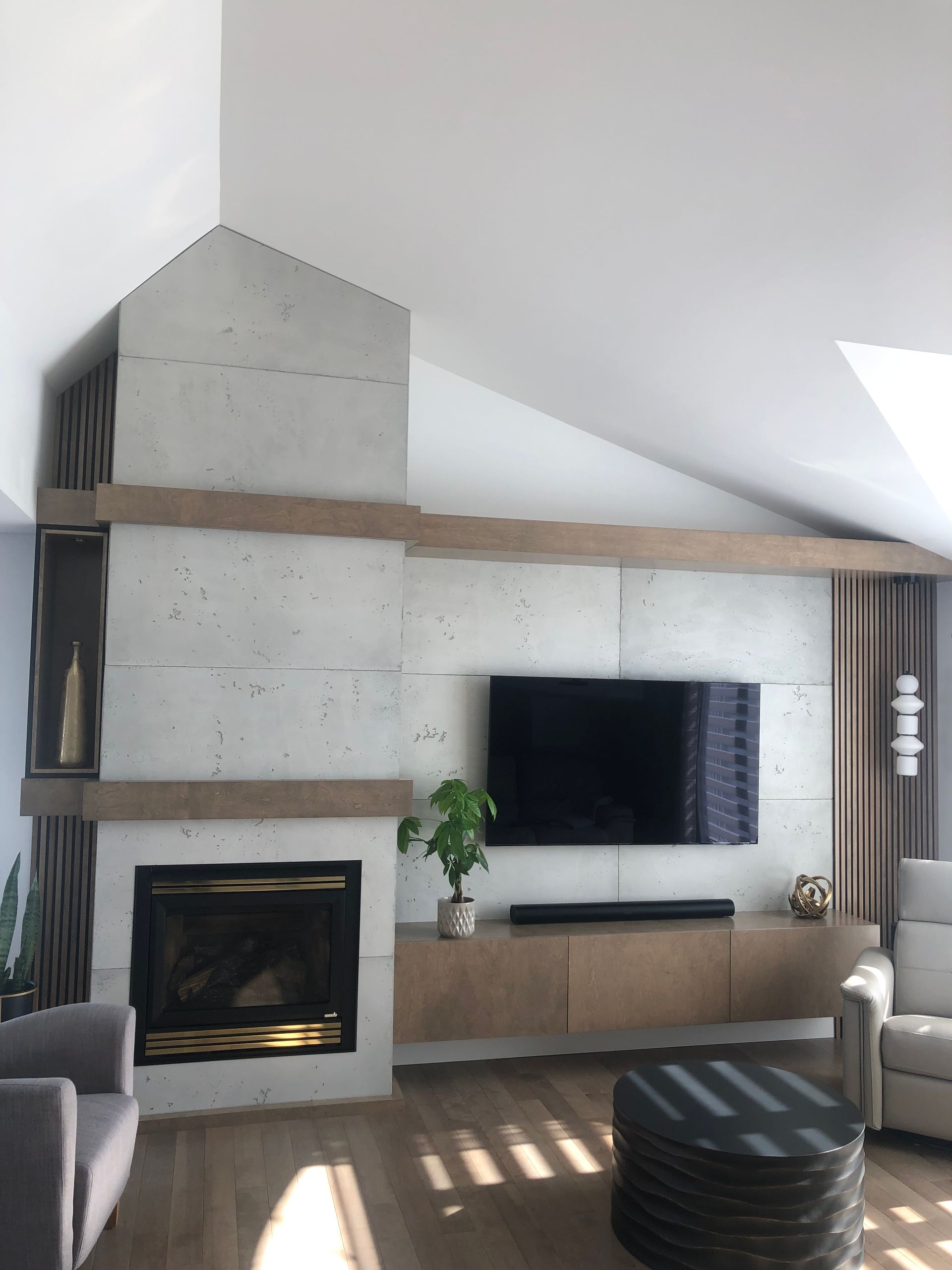 Un mur d'accent en blocs de béton avec des incrustations horizontales en bois, une télévision à écran plat et des armoires, au sein du salon.