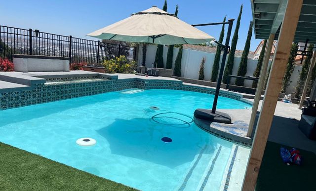 A large swimming pool with a large umbrella on top of it