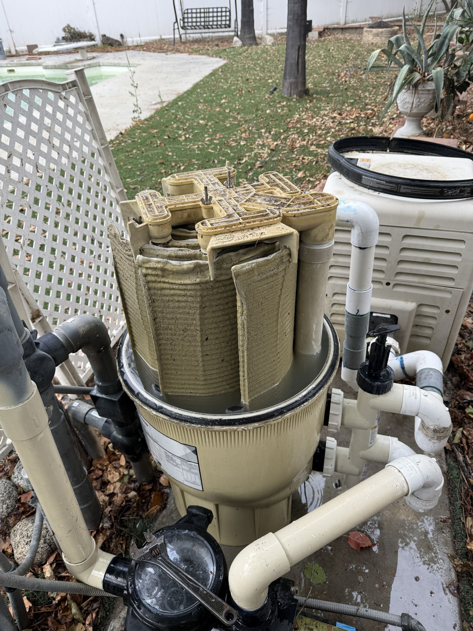 Worn DE filter grids caked with buildup sitting inside an open filter tank before replacement