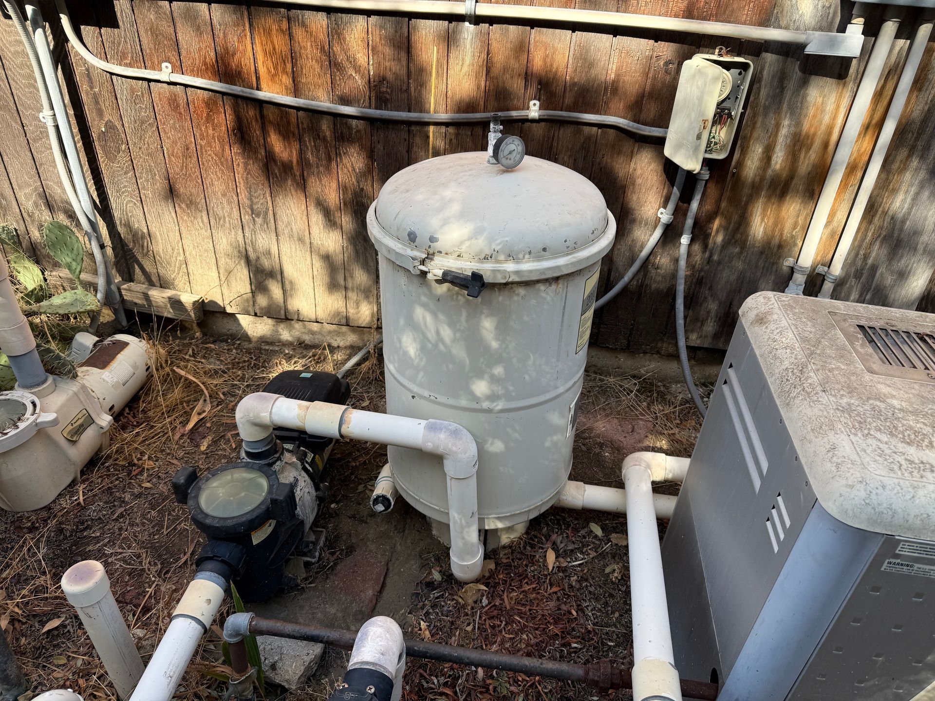 A swimming pool filter is sitting next to a pool pump.
