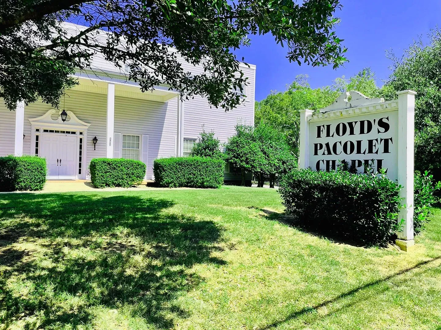 White church with sign reading “Floyd’s Tabernacle” beside a green lawn and trees