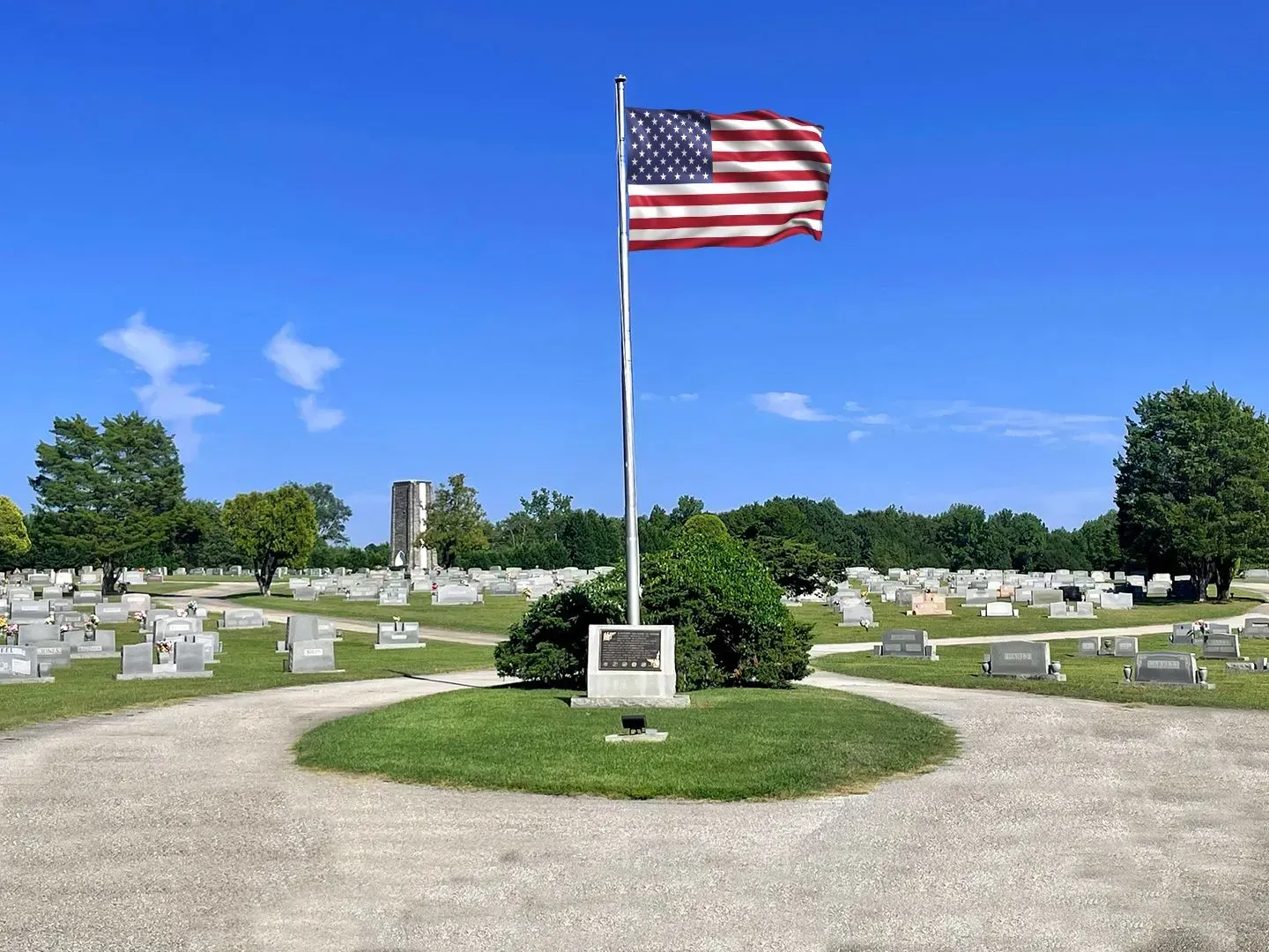 American flag on a pole in a cemetery under a clear blue sky
