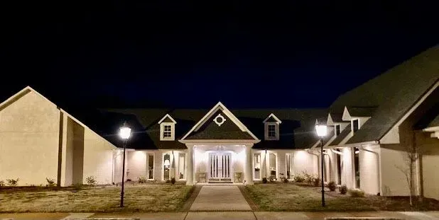 Nighttime view of a lit house with a central entrance and dormer windows