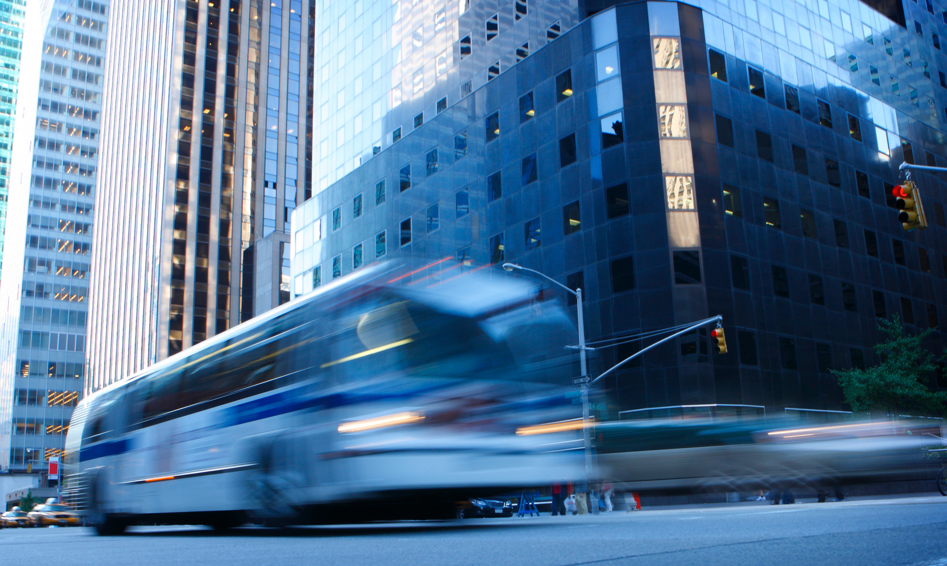 A bus is driving down a city street in front of tall buildings
