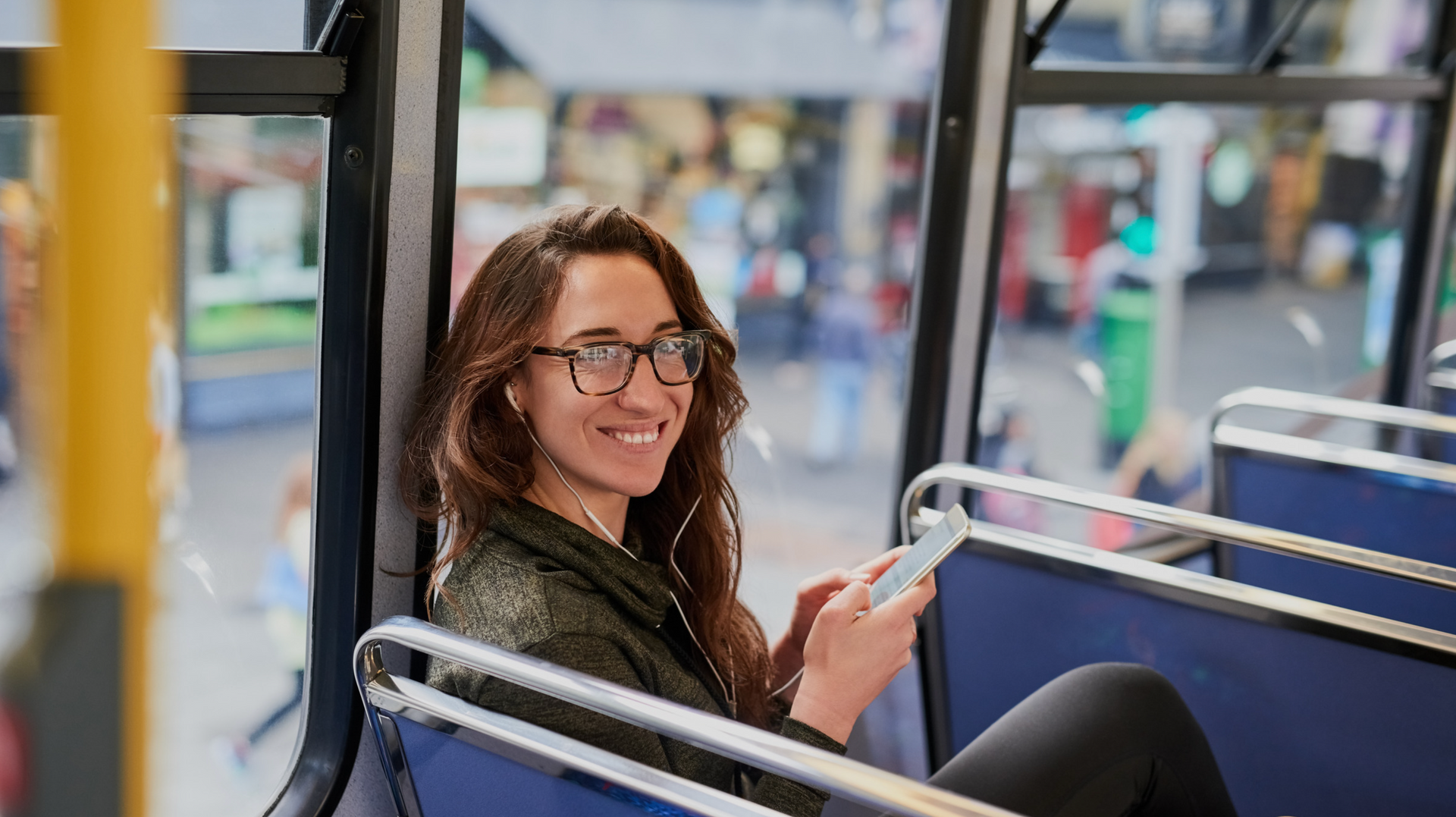 A woman is sitting on a bus looking at her phone.