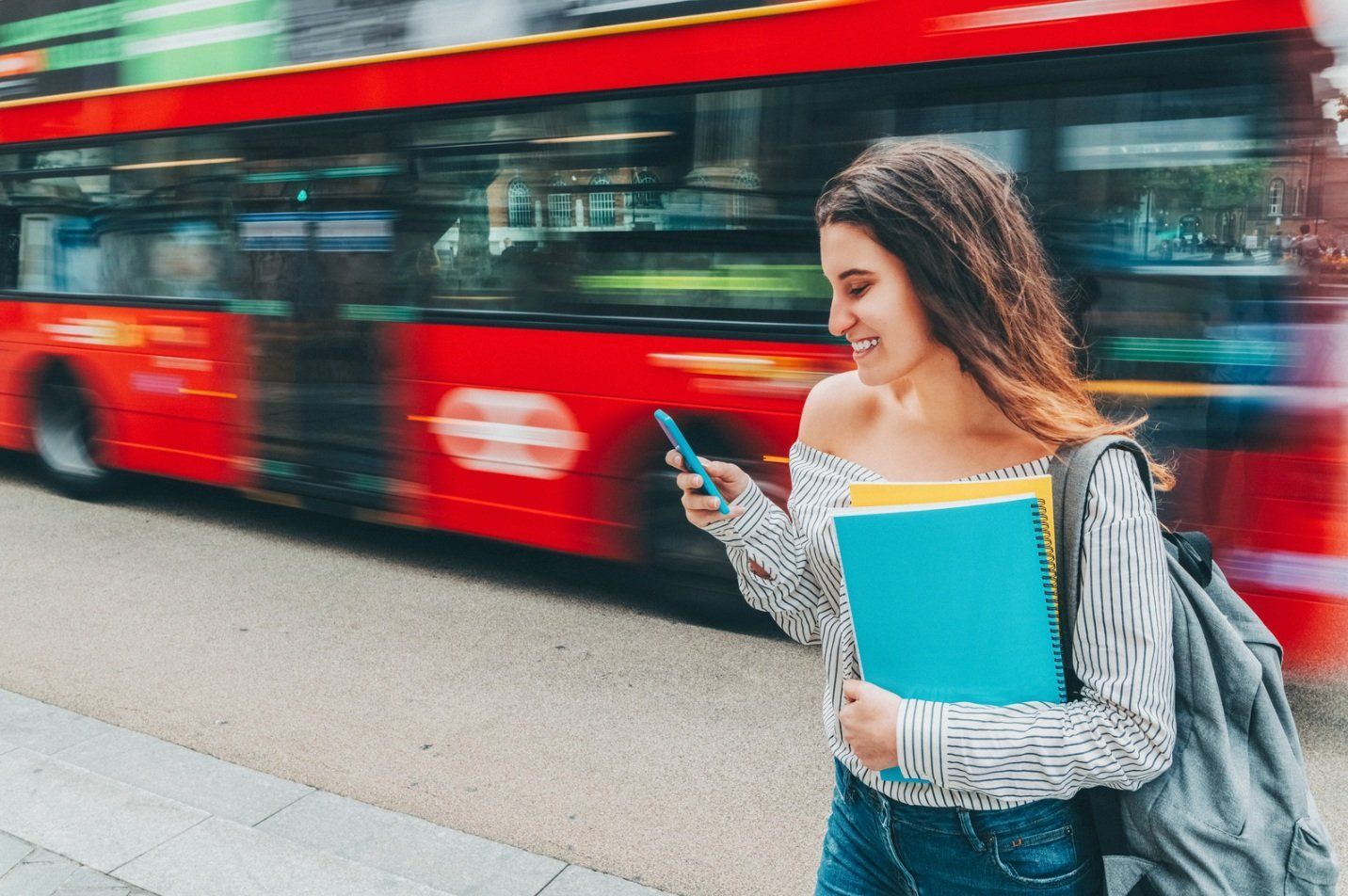 University student checking the campus shuttle rider app while waiting for the bus