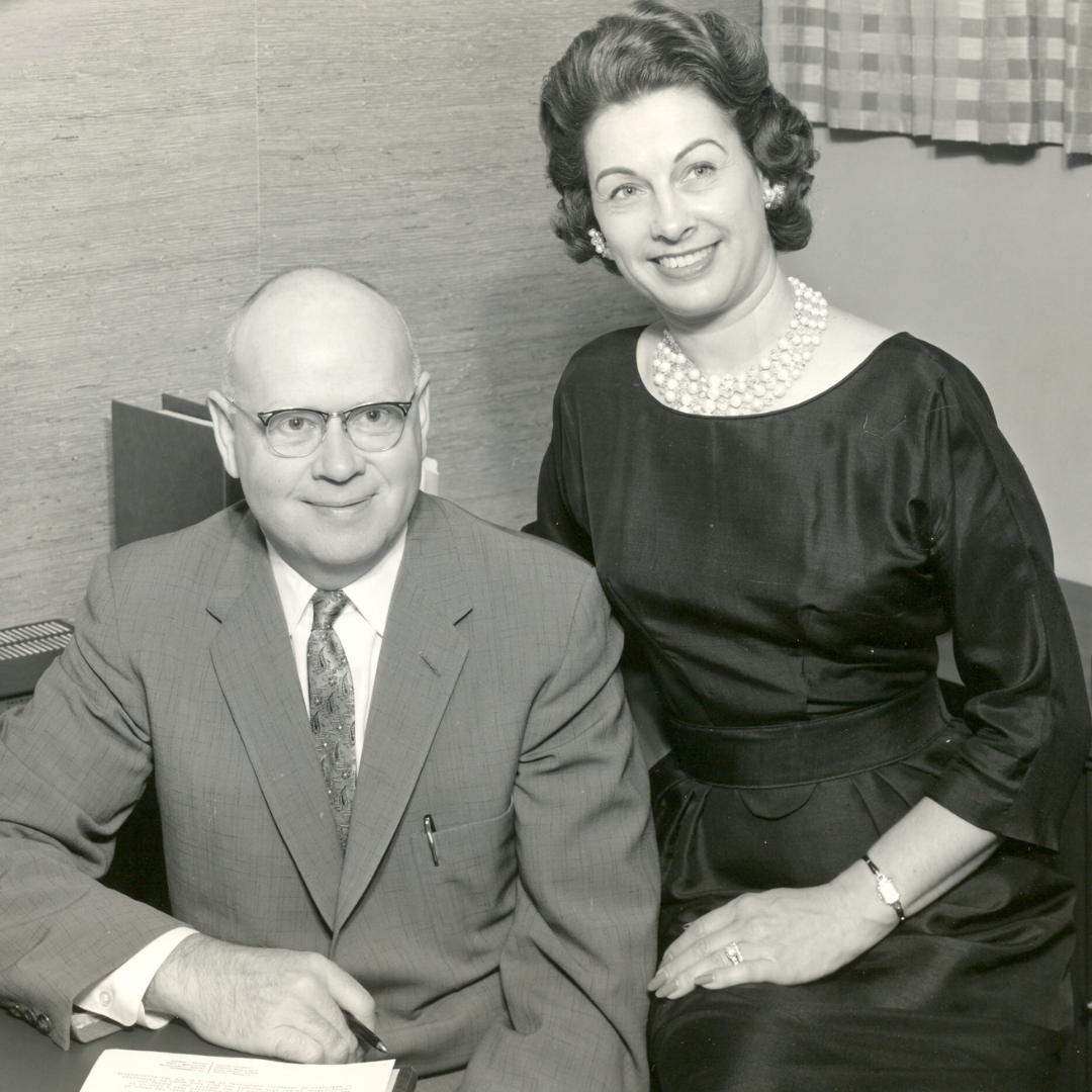 A man in a suit and tie sits next to a woman in a black dress