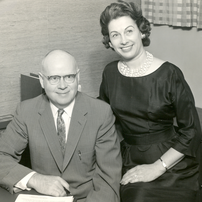 A man in a suit and tie sits next to a woman in a black dress