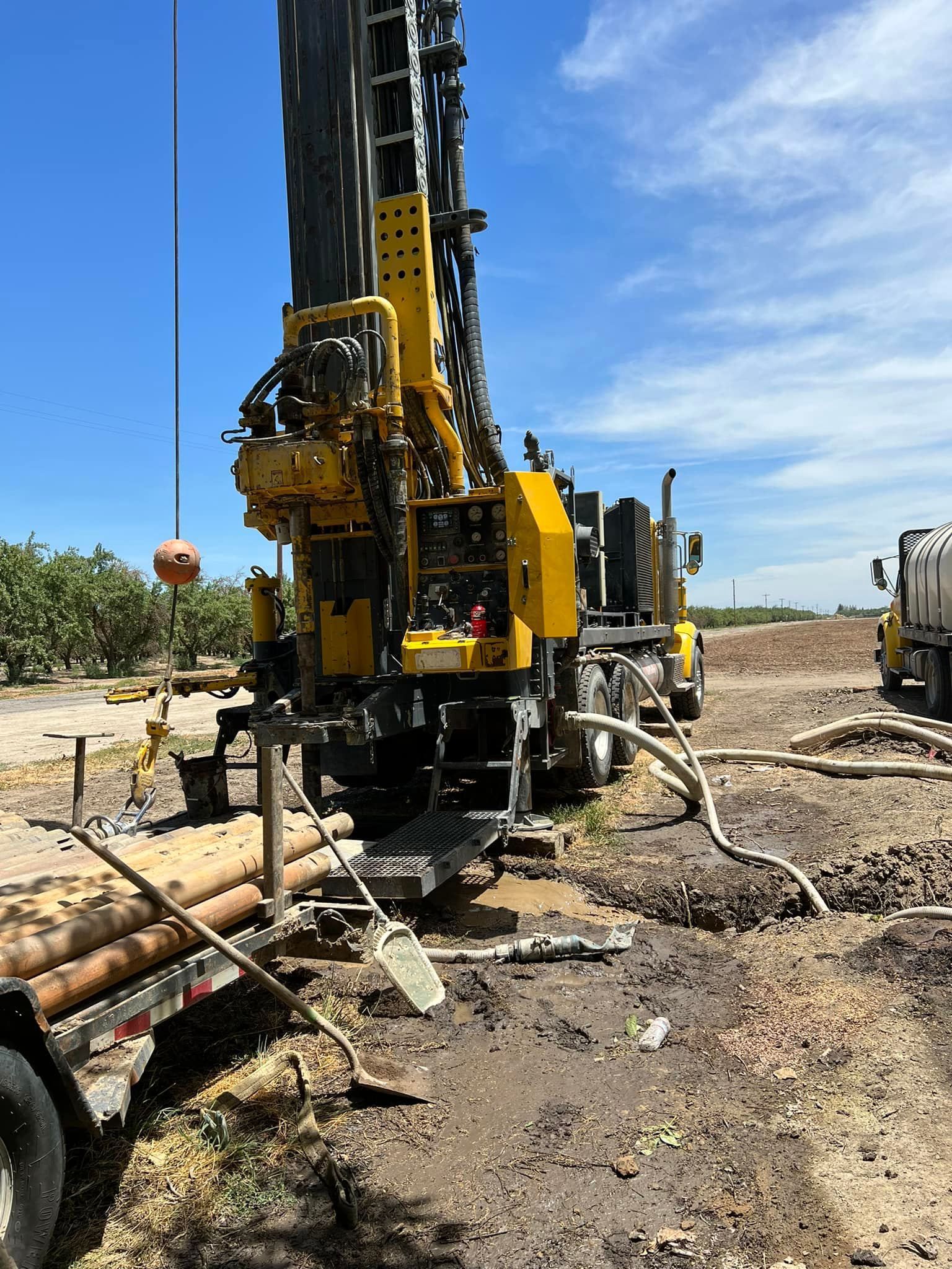 A large yellow machine is sitting on top of a dirt field.