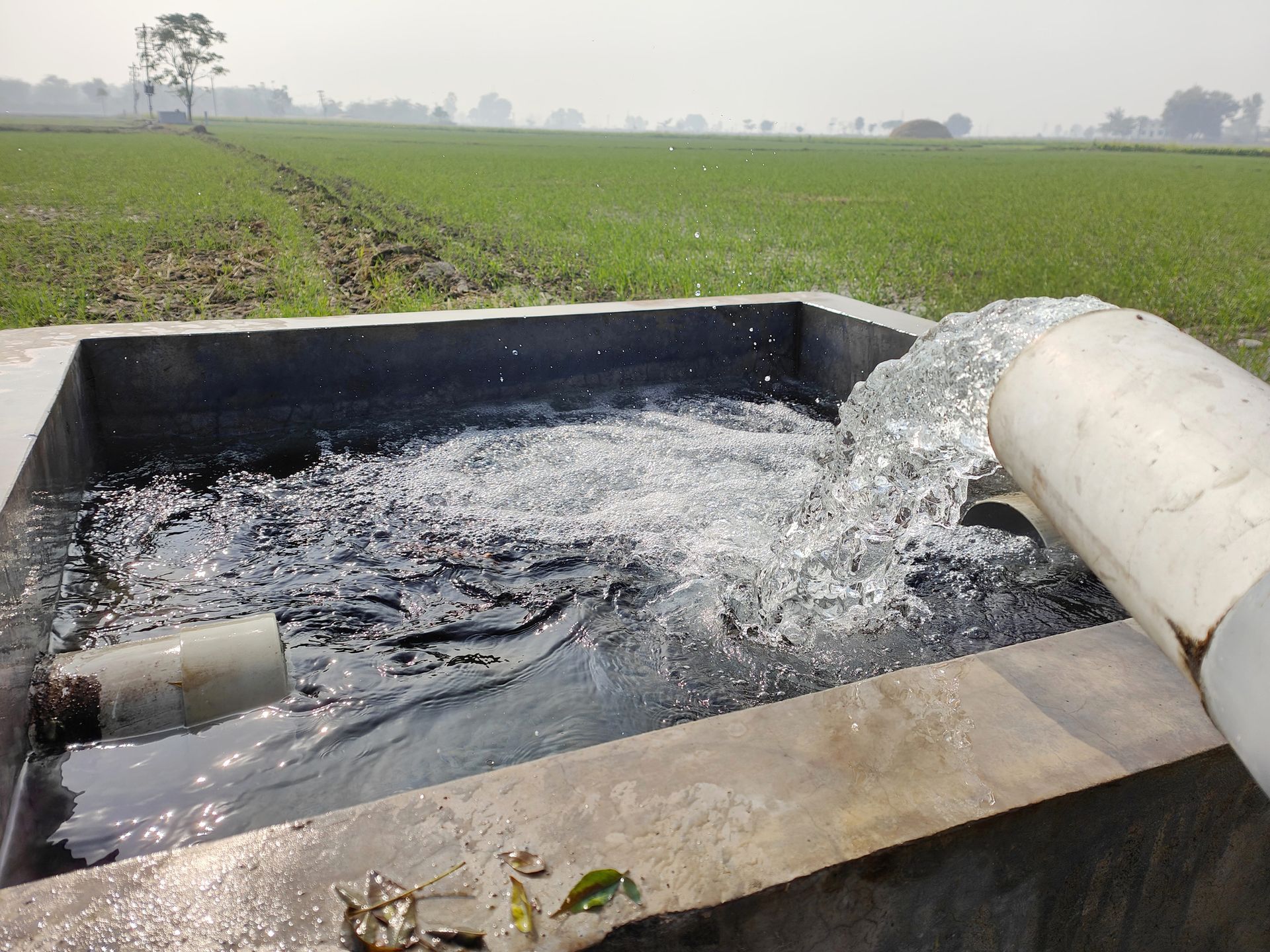 Water is being pumped into a tank in a field.