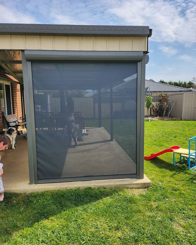 Outdoor patio with a retractable screen, green lawn, and a partially visible dog.