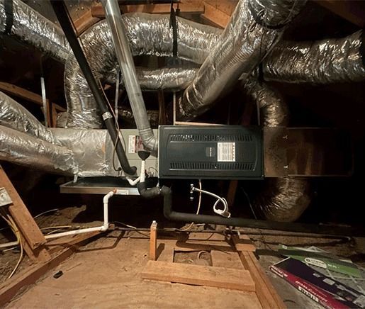 Attic with insulated HVAC ducts and a mounted furnace unit above wooden floor joists
