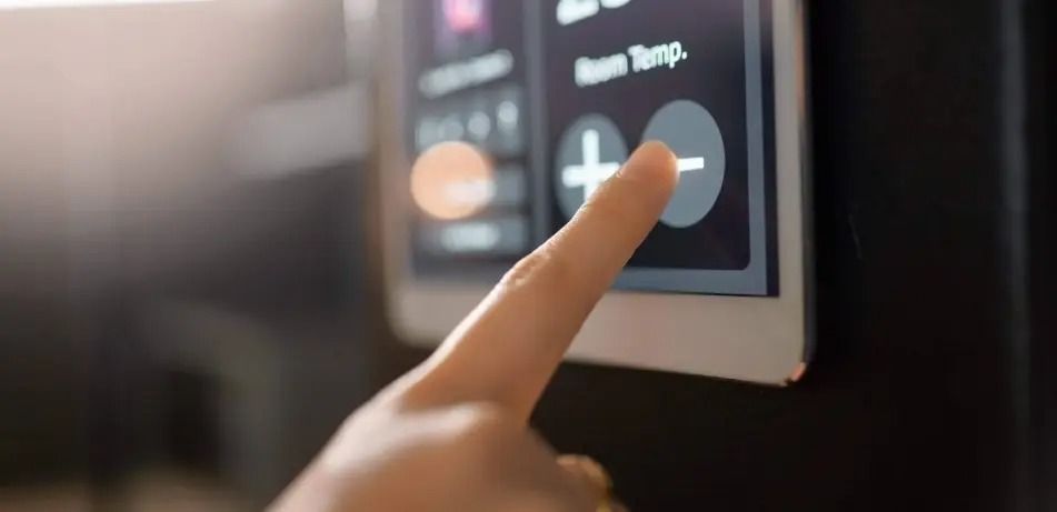 Finger pressing a touchscreen thermostat control with plus and minus buttons