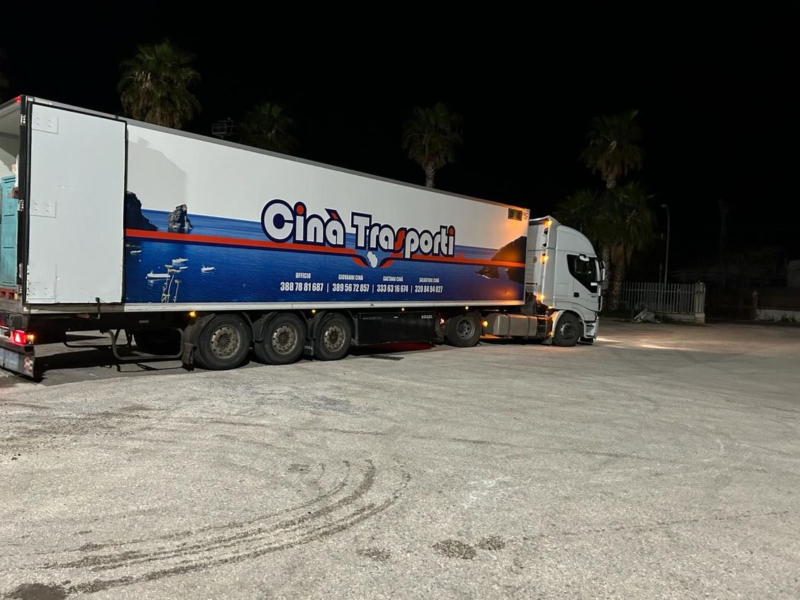 un semirimorchio blu e bianco è parcheggiato in un parcheggio di notte.
