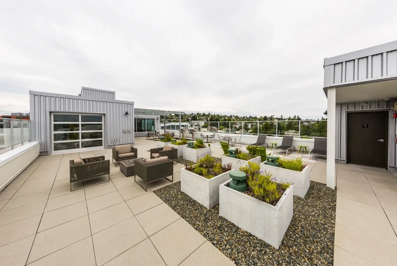 Rooftop lounge area with seating, planters, and city views.