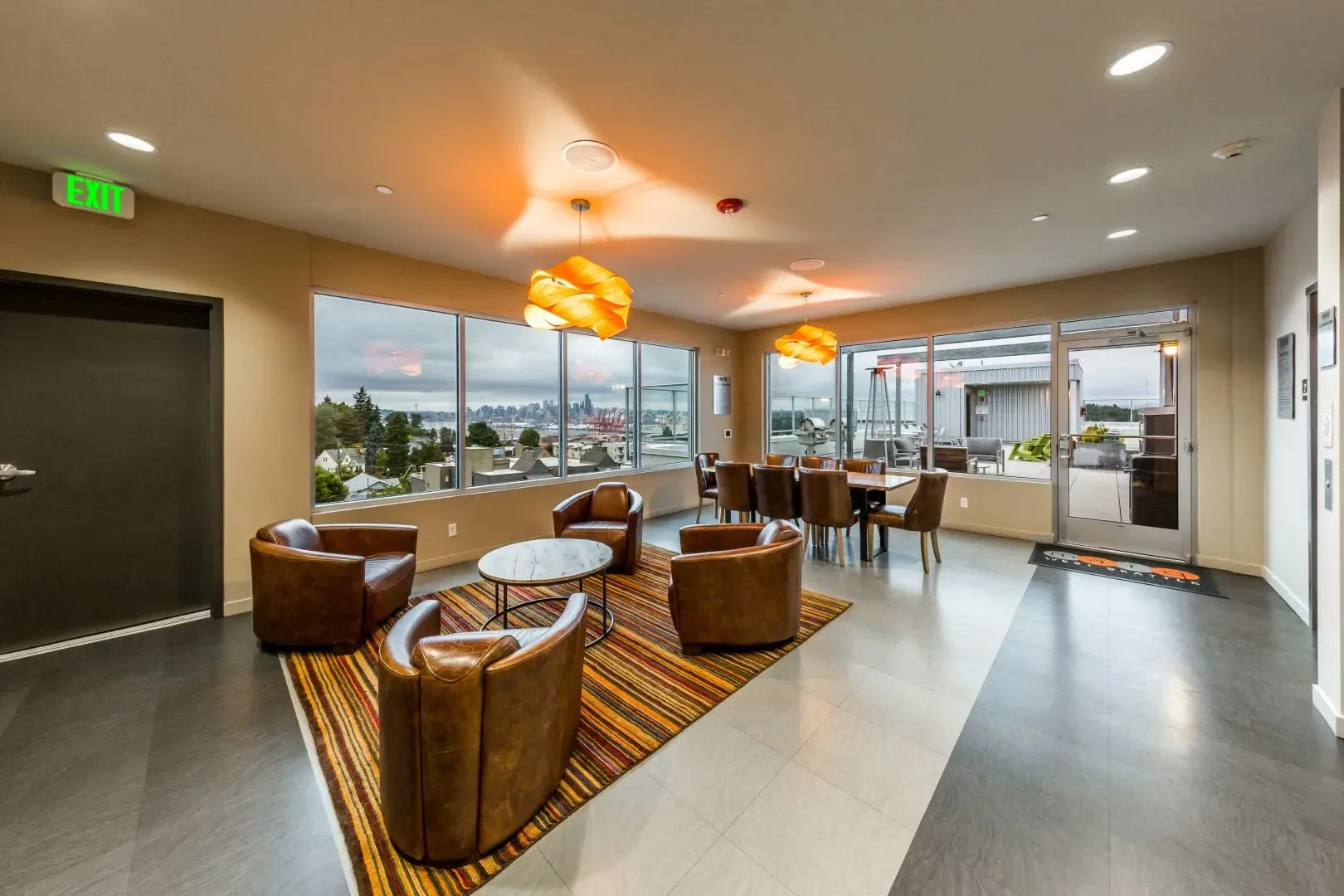 Comfortable lounge area with leather chairs and a dining table overlooking the city skyline.